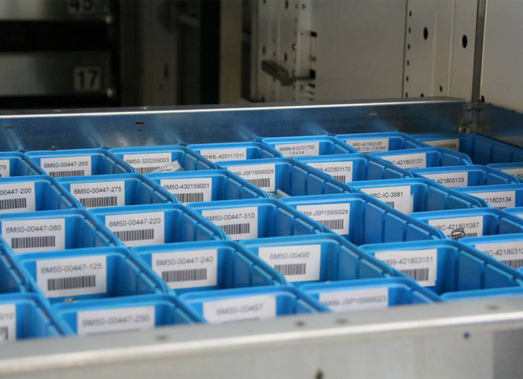 Ausgefahrenes Tablet des Lagerturms bestückt mit sortierten Kleinteilen